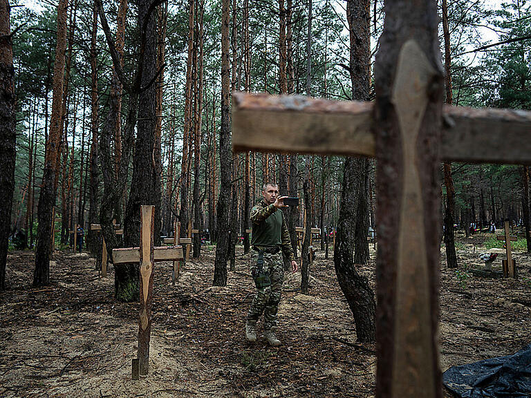 Oleg Kotenko, der Beauftragte für Vermisstenfragen unter besonderen Umständen, filmt mit seinem Smartphone die nicht identifizierten Gräber von Zivilisten und ukrainischen Soldaten im kürzlich zurückeroberten Gebiet von Isjum. Foto: Evgeniy Maloletka/AP/dpa