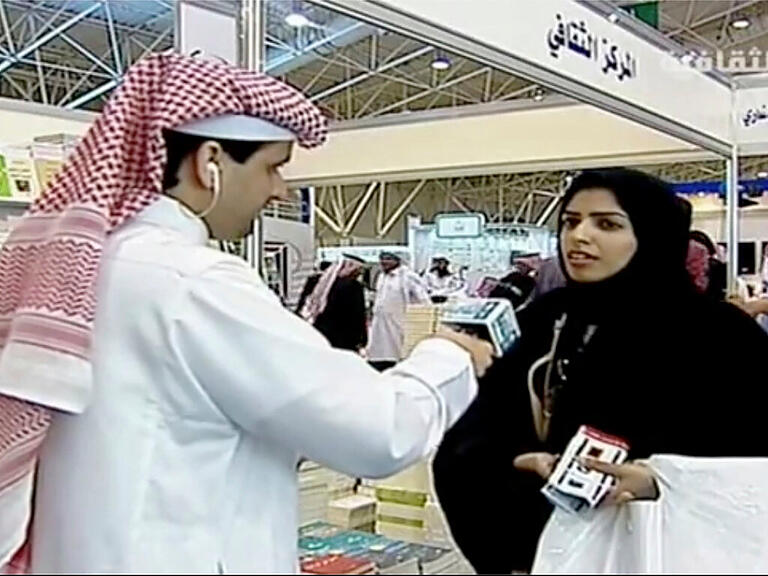 SCREENSHOT - Dieses Videostandbild des saudischen Staatsfernsehens zeigt Salma al-Shehab (r), Doktorandin und Frauenrechtlerin, im Gespräch mit einem Journalisten auf der Riad International Book Fair im März 2014. Foto: Uncredited/Saudi state television/AP/dpa - ACHTUNG: Verwendung nur bis zum 02.09.2022