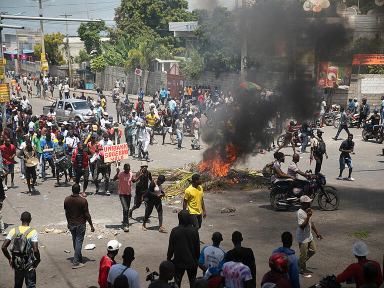 Menschen demonstrieren in der Nähe brennender Reifen während einer Demonstration, bei der der Rücktritt des haitianischen Premierministers Henry und eine bessere Lebensqualität gefordert werden. Foto: Odelyn Joseph/AP/dpa